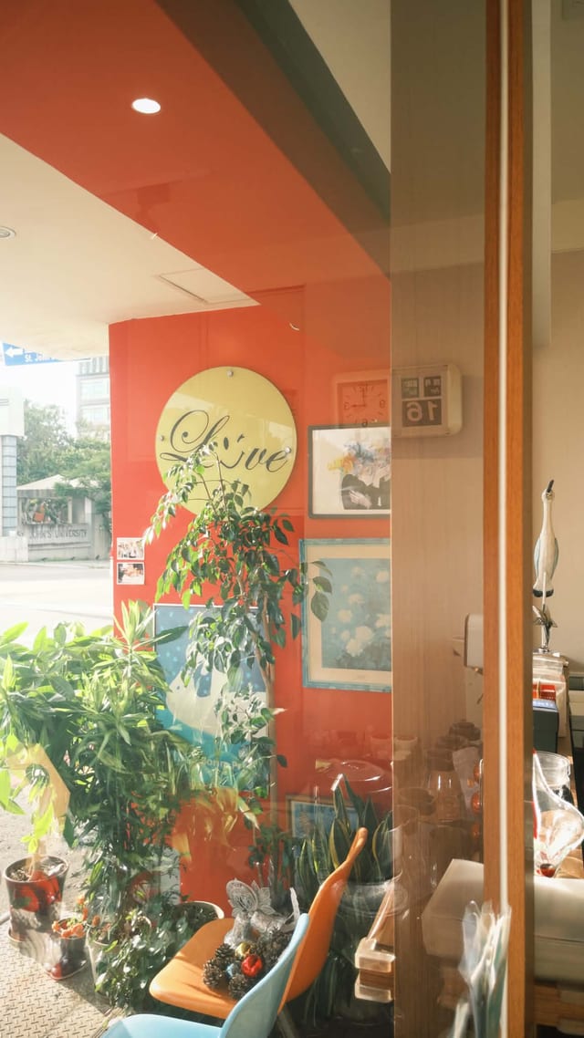 莉香リカ在淡水店內裝潢一角，橘牆與Love吊飾